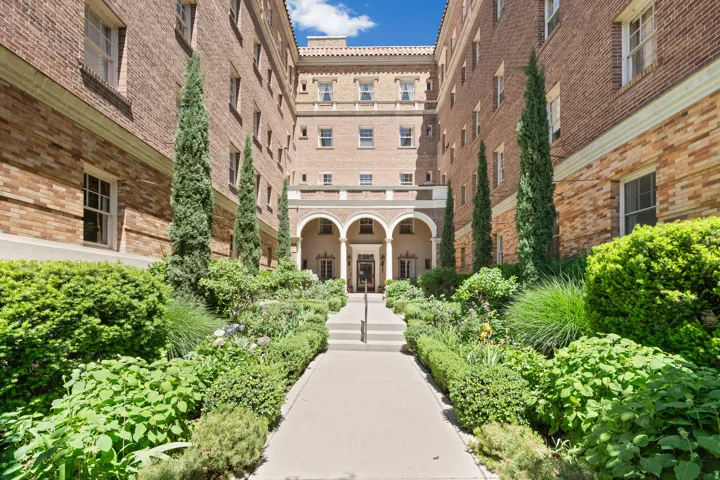 Exterior brick building featuring a central walkway and manicured landscaping