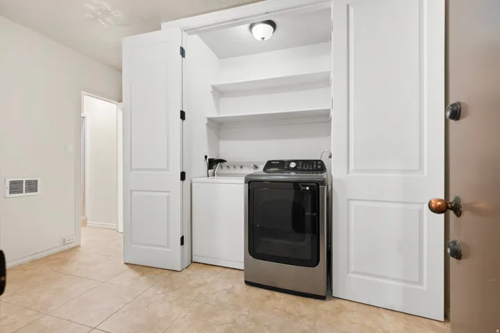 Laundry closet featuring bi-fold doors, integrated shelving, and a ceiling-mounted light fixture