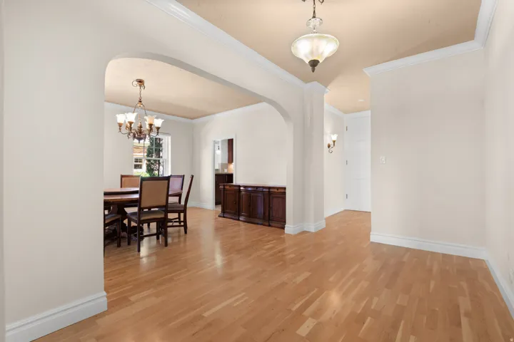 Hardwood flooring throughout, arched doorway, crown molding, wall sconces, and built-in wood cabinetry