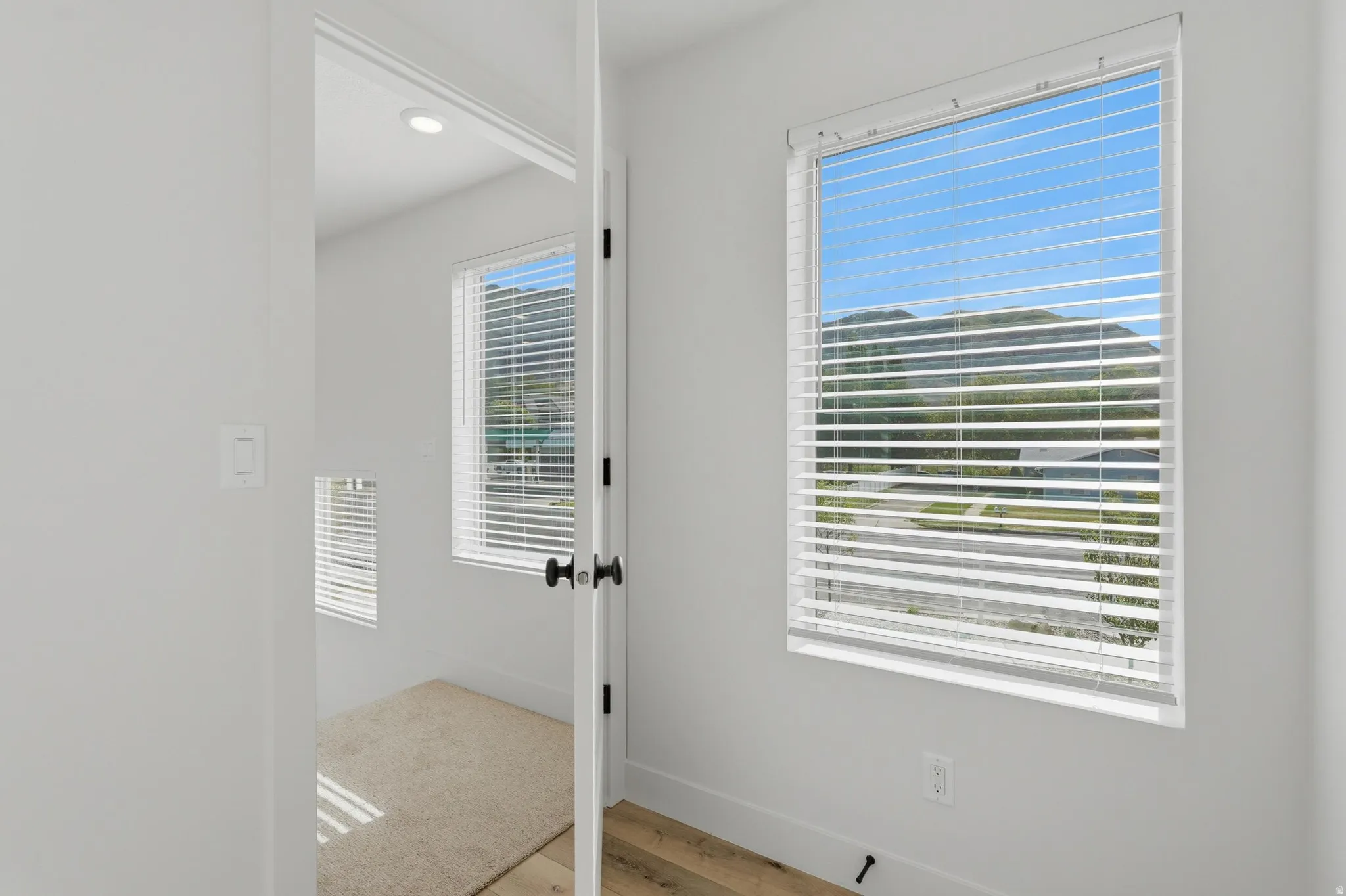 Bright room featuring mountain scenery, window blinds, light-colored walls, recessed lighting, and wood-finish flooring