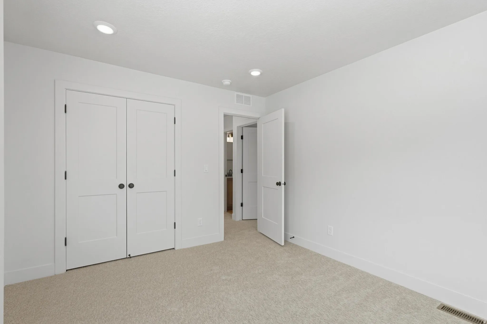Neutral toned carpeting extending throughout, with white walls and baseboards