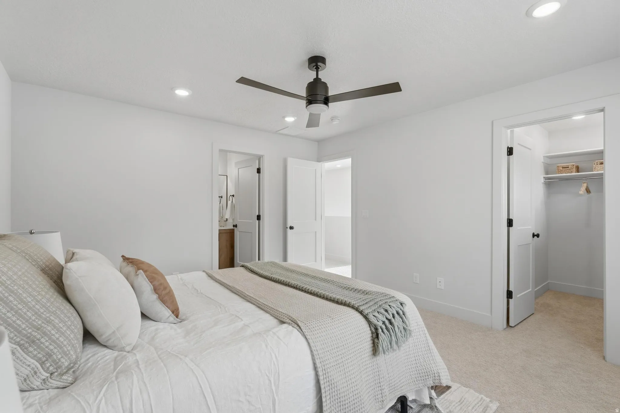 Bright bedroom featuring neutral-toned carpet, recessed lighting, and a dark-toned ceiling fan