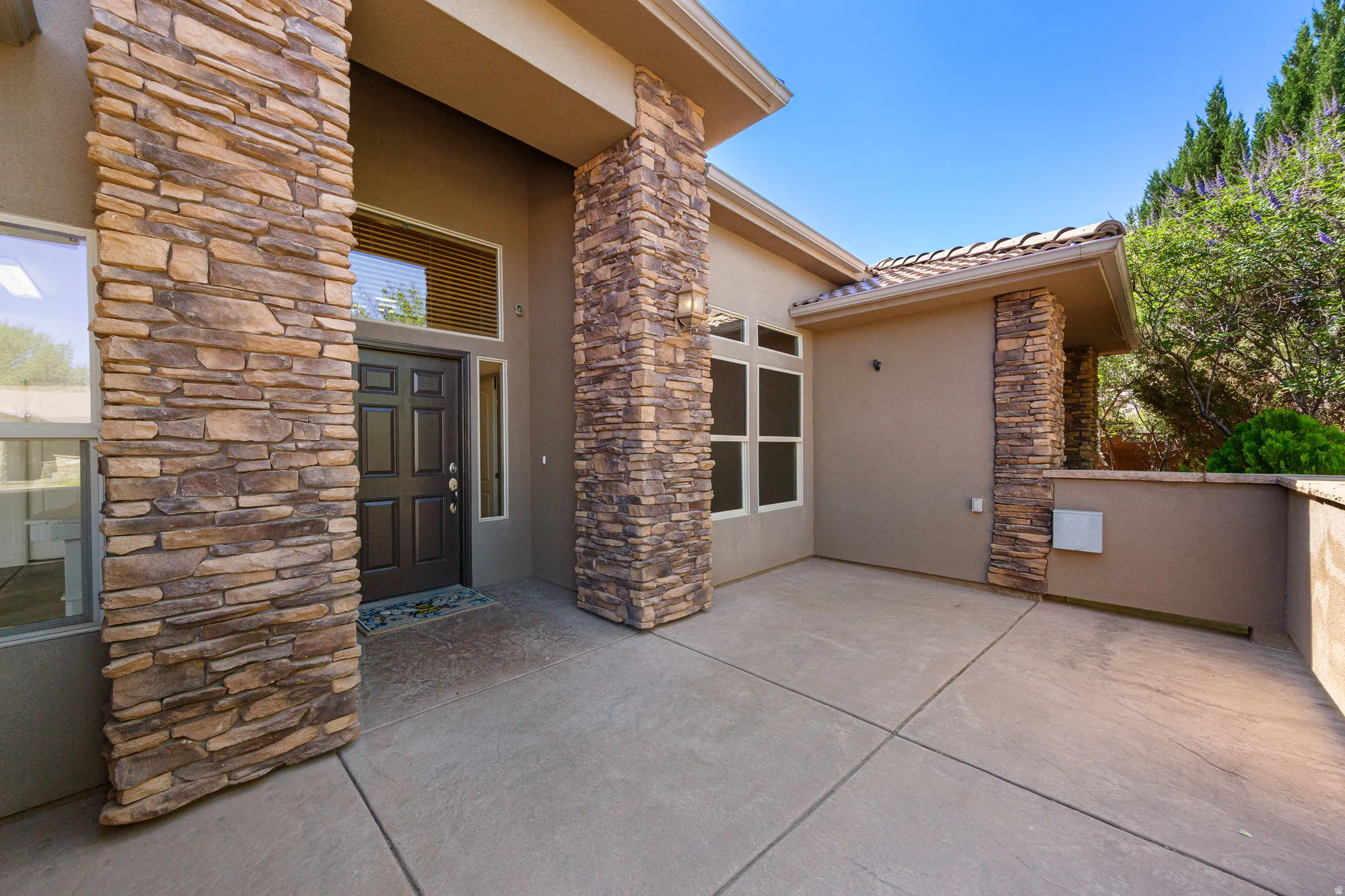 Entryway featuring stacked stone columns, a paneled door, and a transom window