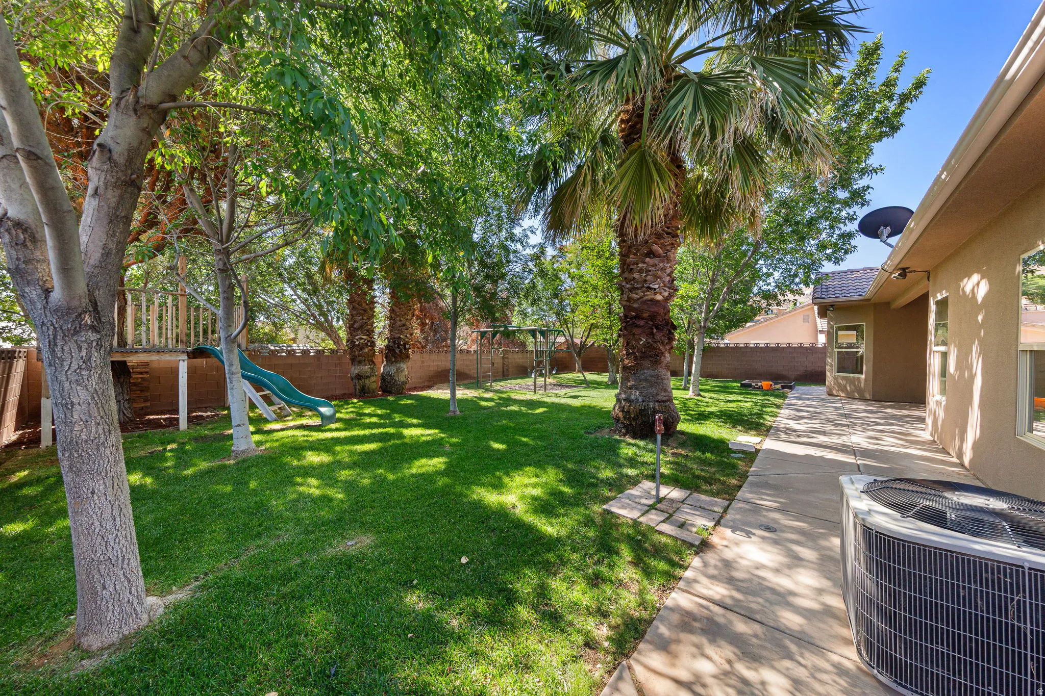 Expansive backyard featuring a large grass lawn, mature trees, and a substantial patio area