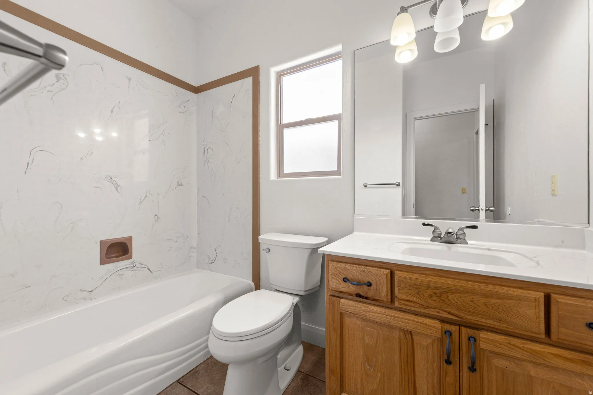 Bathroom featuring a wood-finish vanity with a white countertop and integrated sink, a large mirror, and a three-light vanity fixture