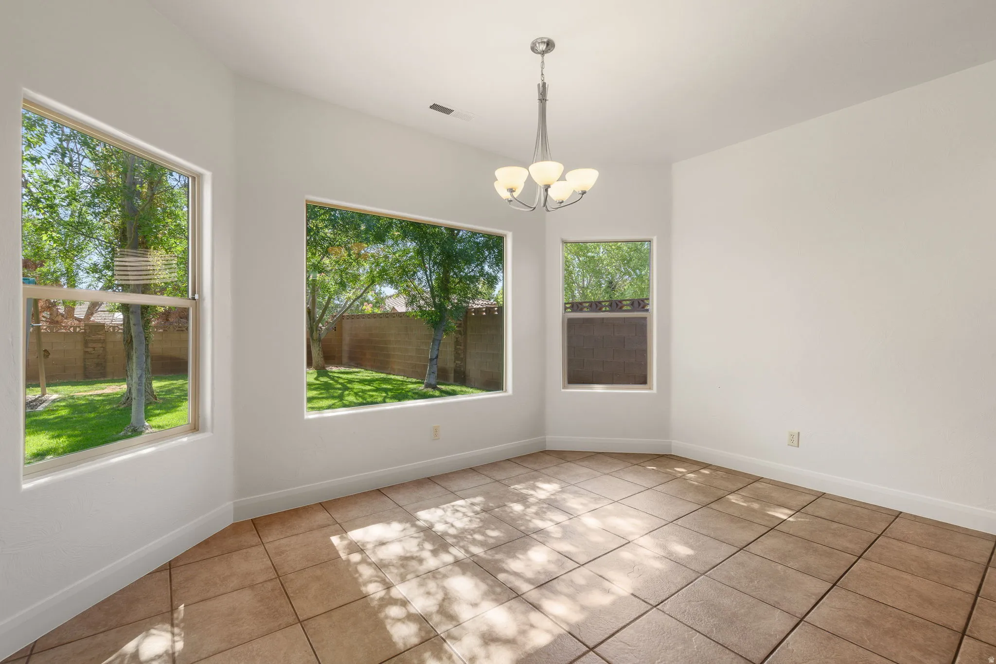 Room with multiple windows, ceramic tile flooring, and a contemporary chandelier