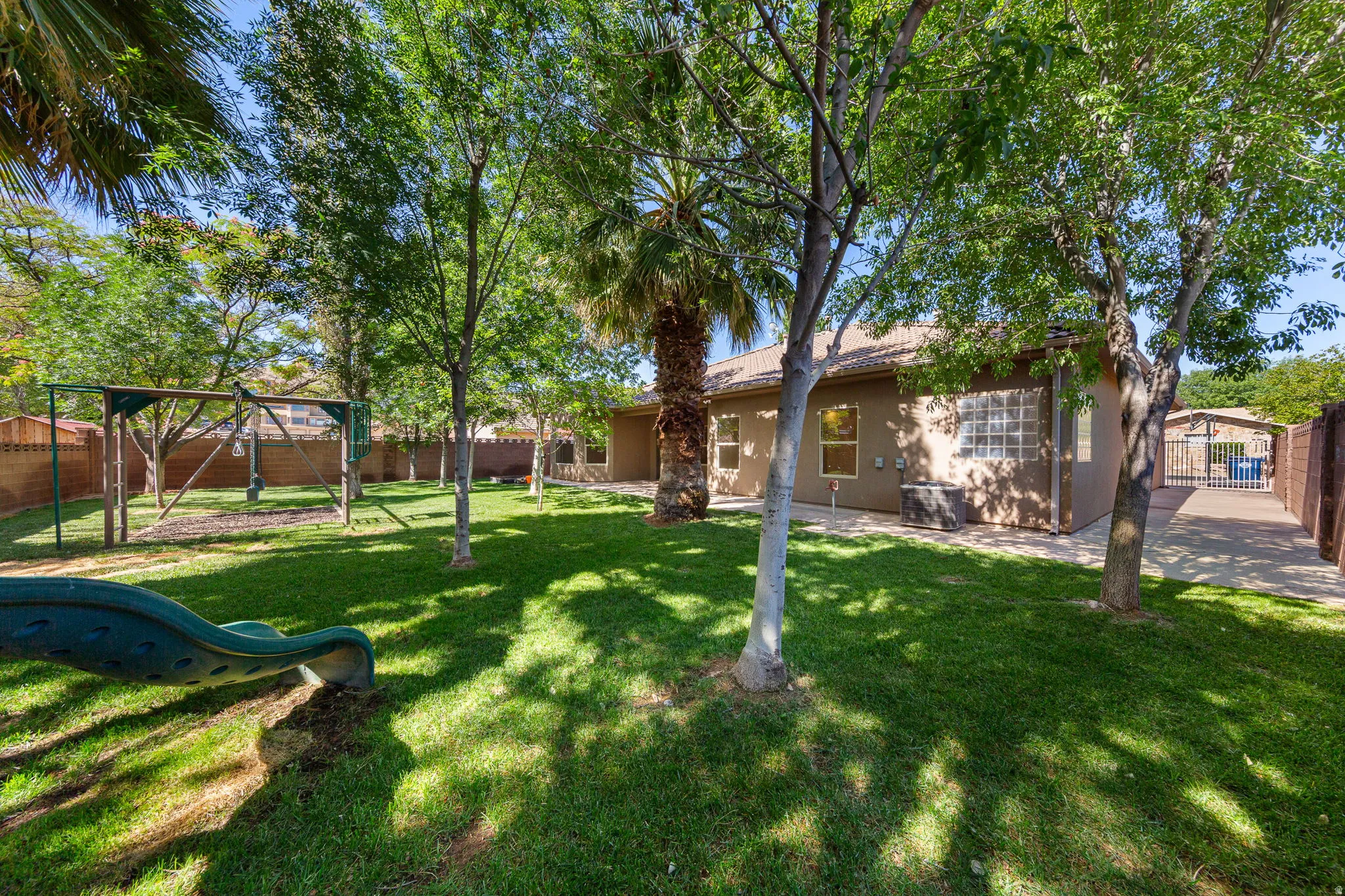 Expansive green lawn with mature trees and a privacy fence