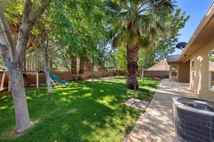 Expansive backyard featuring a large grass lawn, mature trees, and a substantial patio area