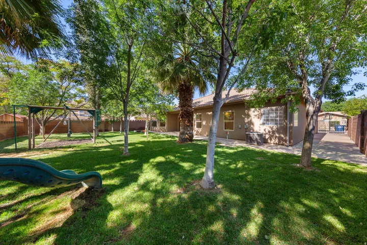 Expansive green lawn with mature trees and a privacy fence