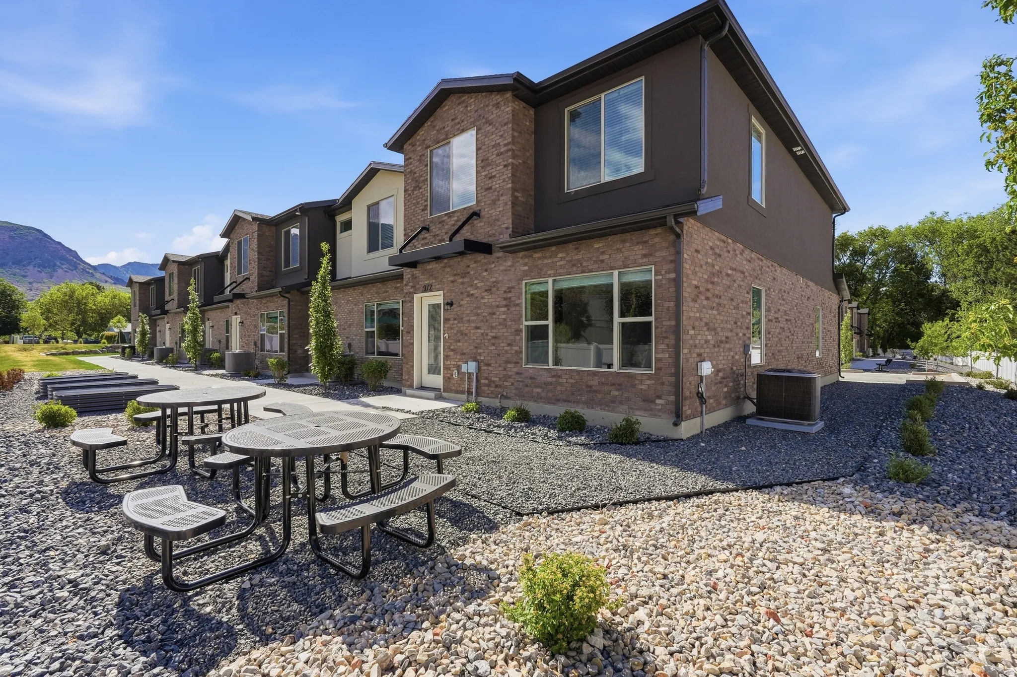 Modern townhome exterior featuring brick and panel siding, multiple windows, and a paved walkway
