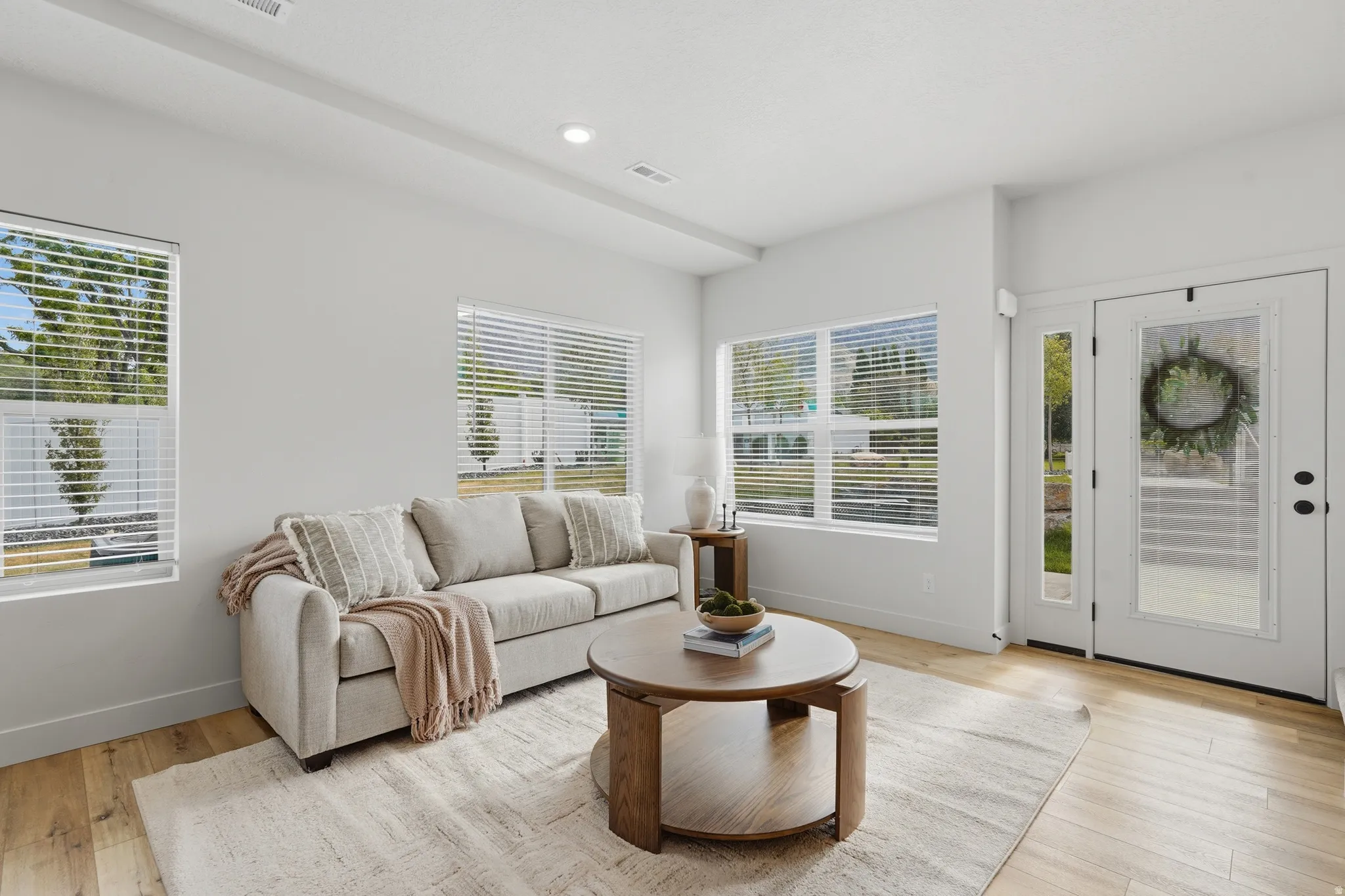 Bright living space featuring wood-finish flooring, recessed lighting, and multiple windows