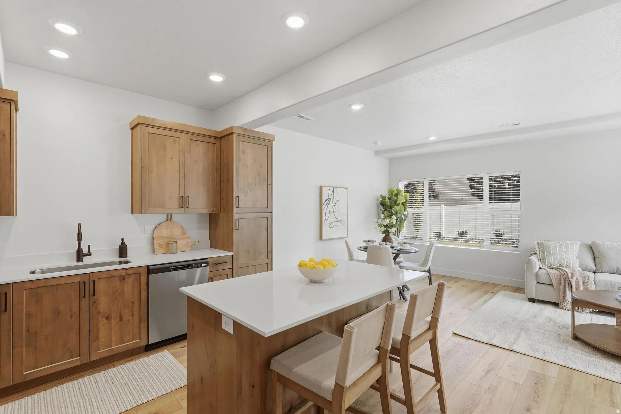 Open-concept living space featuring wood-finish flooring, recessed lighting, and a kitchen island with seating