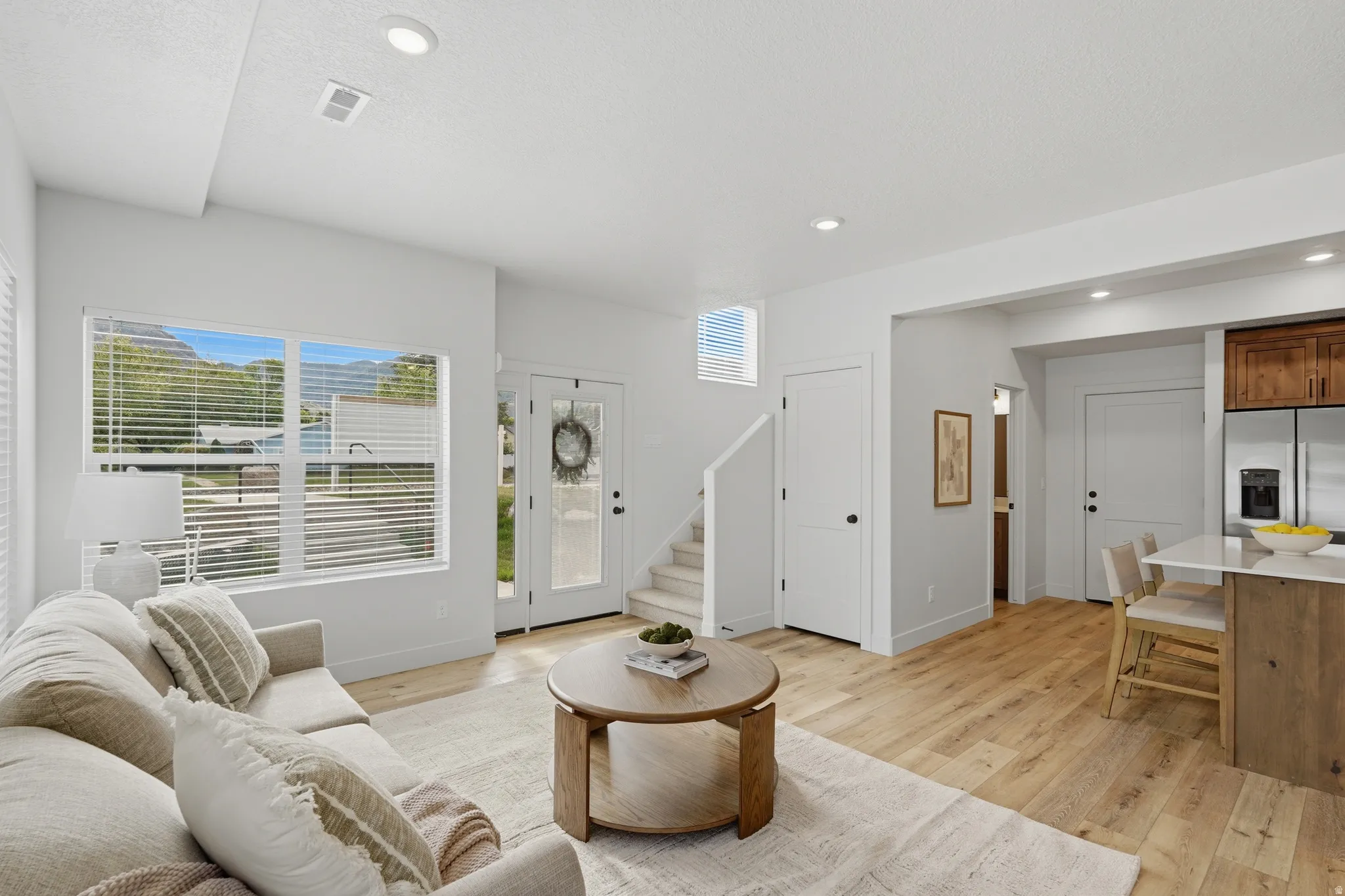 Open-concept living space featuring wood-finish flooring, recessed lighting, and a kitchen island with seating