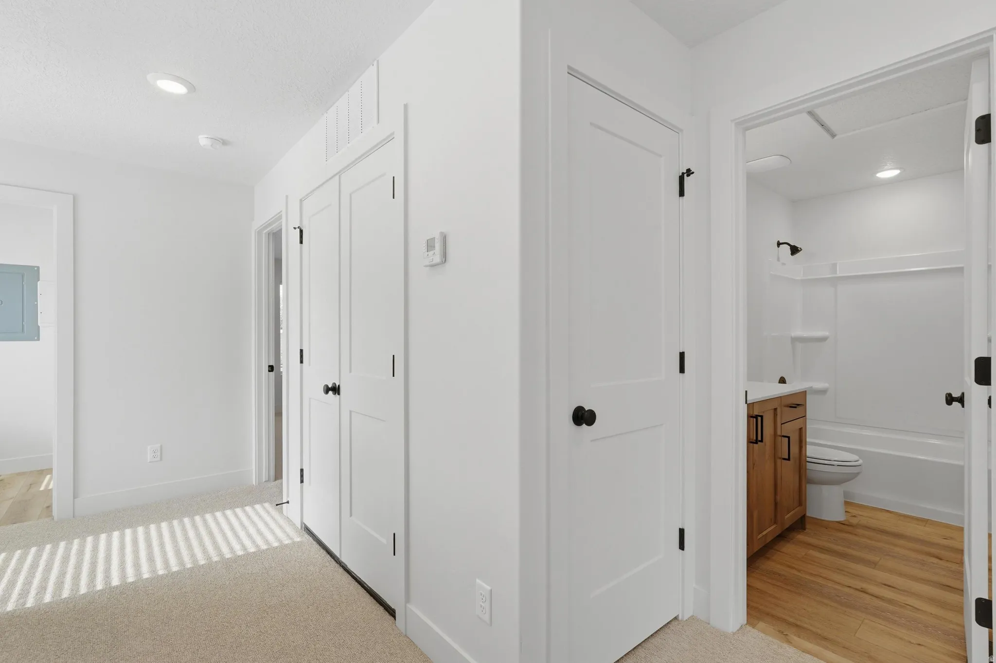 Hallway featuring recessed lighting, white doors with matte black hardware, and neutral carpet