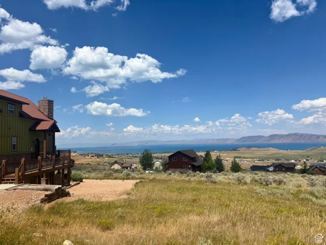 Expansive outdoor deck with wood railing, offering broad scenery of the distant lake and mountain range