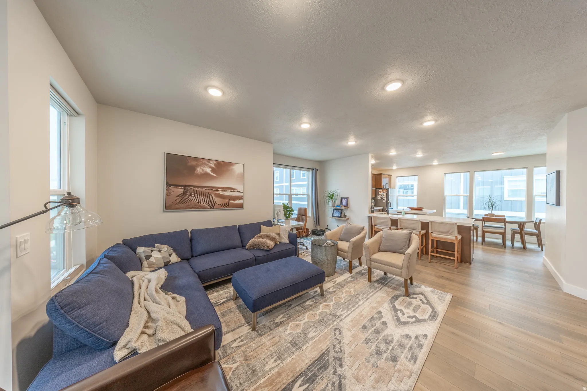 Open-concept living space featuring wood-finish flooring, recessed lighting, and ample natural light from multiple windows