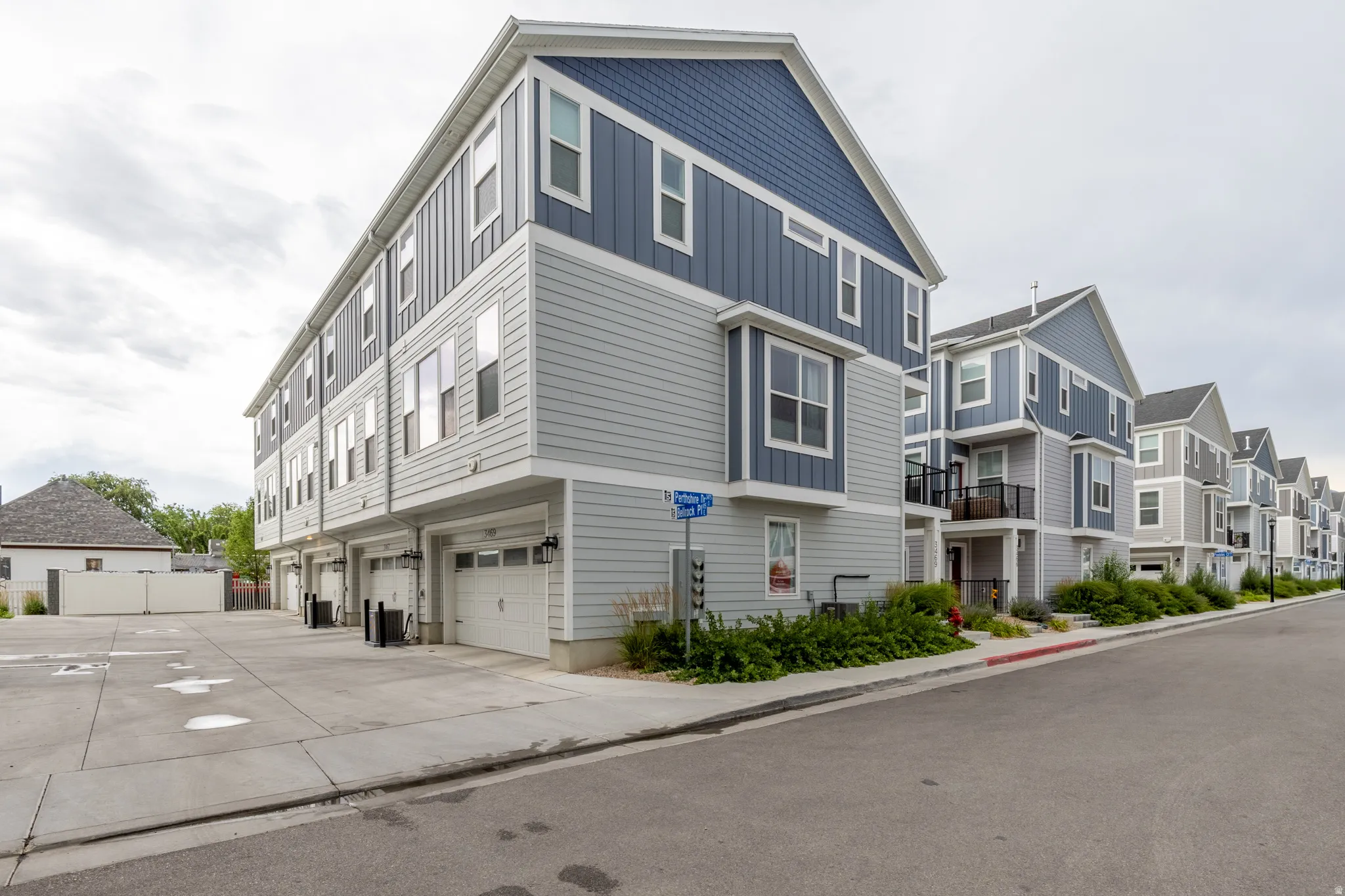 Modern multi-story facade featuring light gray horizontal siding and contrasting blue vertical siding