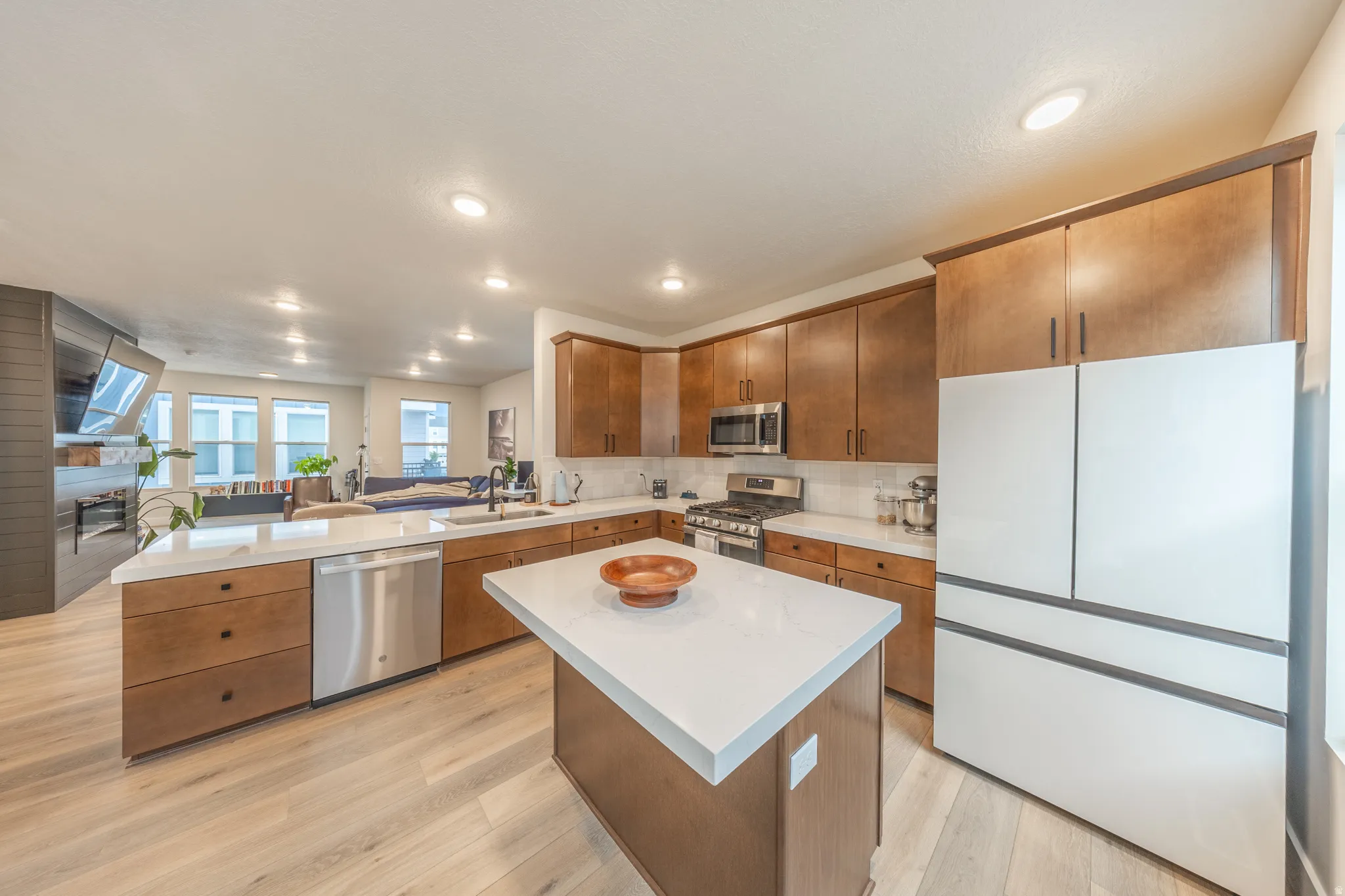 Modern kitchen featuring wood-finish flooring, recessed lighting, and a kitchen island with a light-colored countertop
