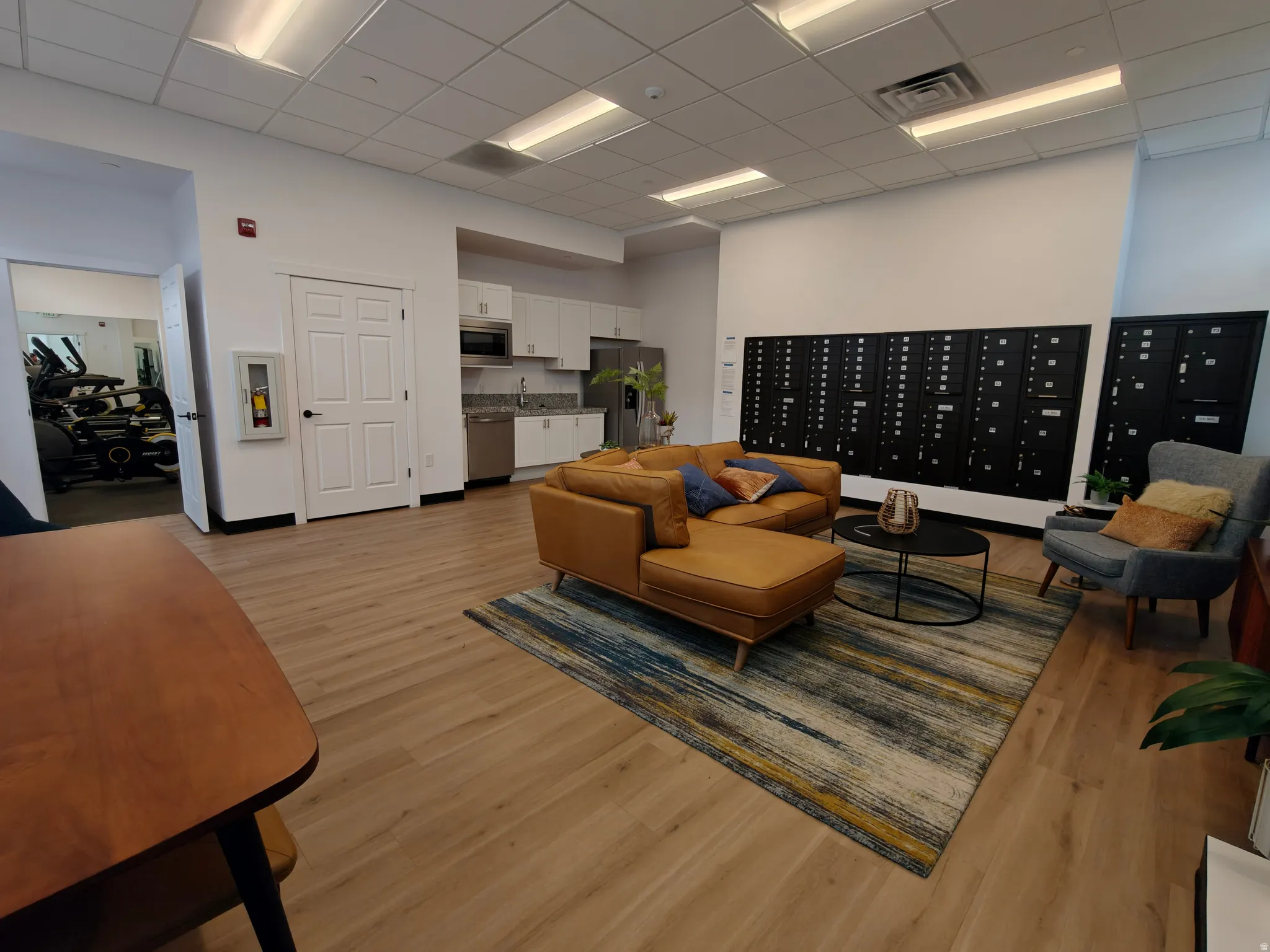 Open-concept common area featuring wood-finish flooring, a contemporary kitchenette with stainless steel appliances, and built-in mailboxes
