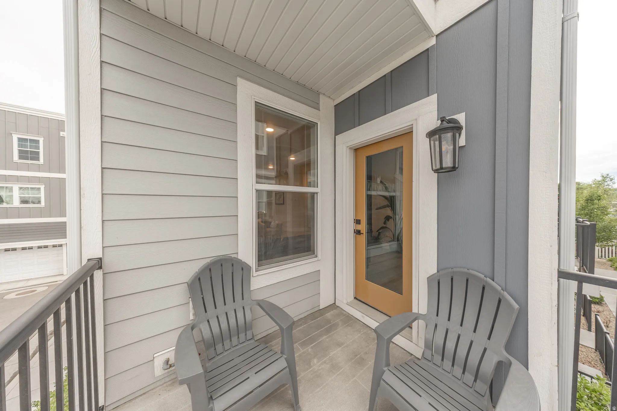 Inviting private balcony featuring light gray siding, dark gray board and batten siding, and a warm wood-finish entry door with clear glass
