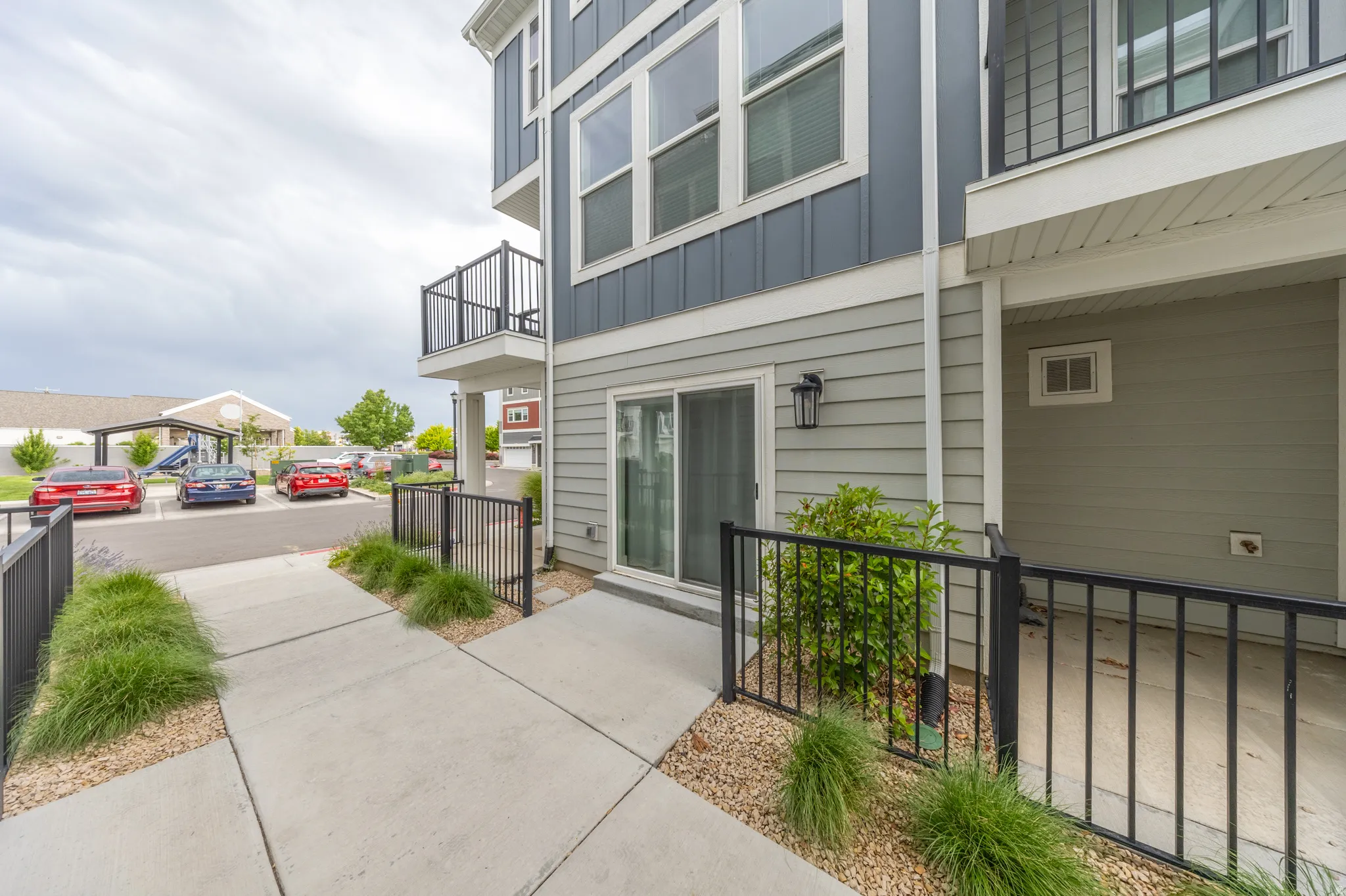 Townhome exterior featuring horizontal siding in two tones, a ground-level patio with black metal railing, and a sliding glass door entry