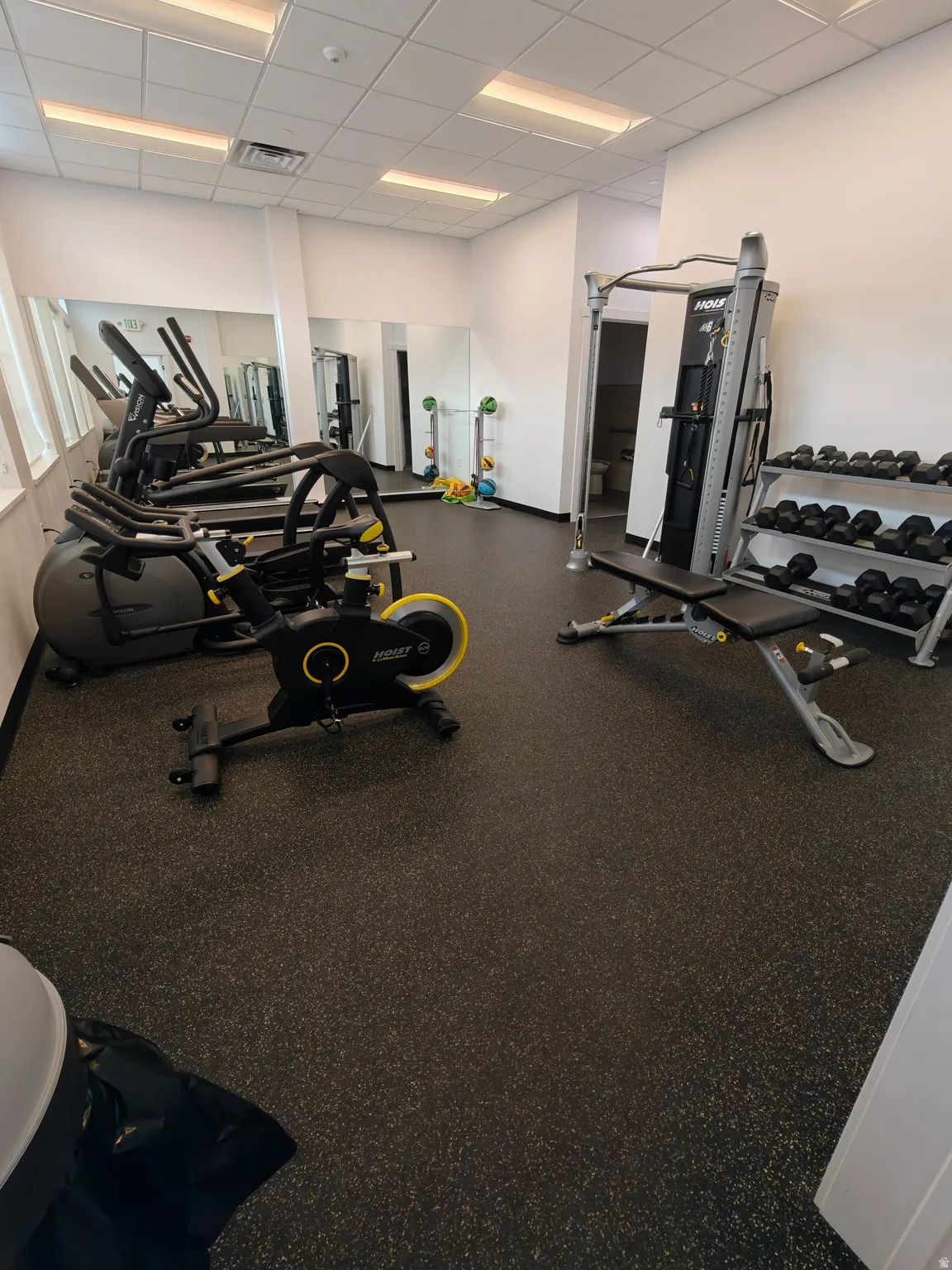 Fitness center featuring resilient rubber flooring, perimeter mirrors, and recessed lighting