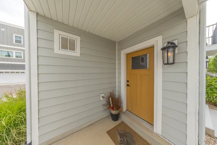 Inviting entryway featuring a warm yellow door with upper glass panel, complemented by a black lantern-style wall sconce