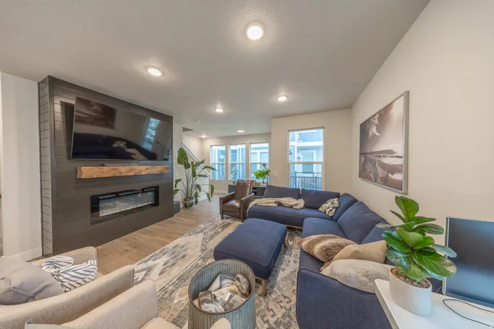 Living area featuring a floor-to-ceiling accent wall with a linear electric fireplace, wood mantel, and integrated television mount