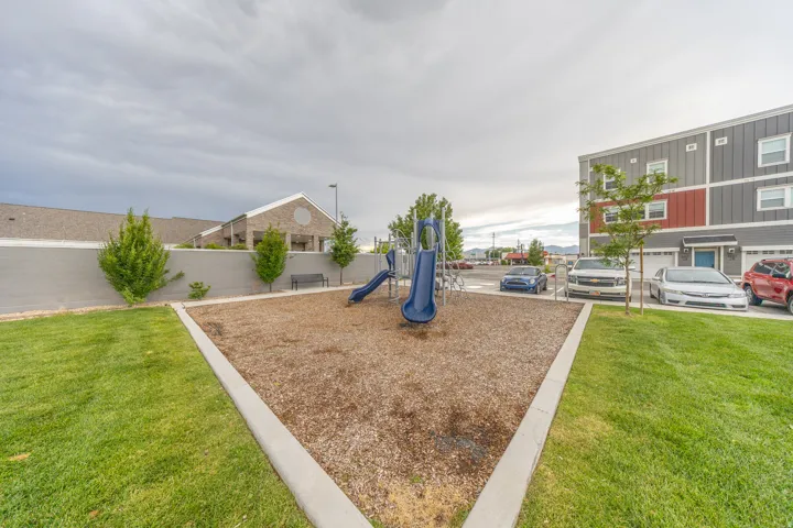 Recreational area featuring a bark-mulch surface with two blue slides and perimeter concrete curbing