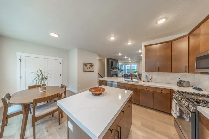 Bright kitchen with a spacious central island featuring a light-toned countertop, wood-finish flooring, recessed lighting, stainless steel appliances, and abundant cabinetry