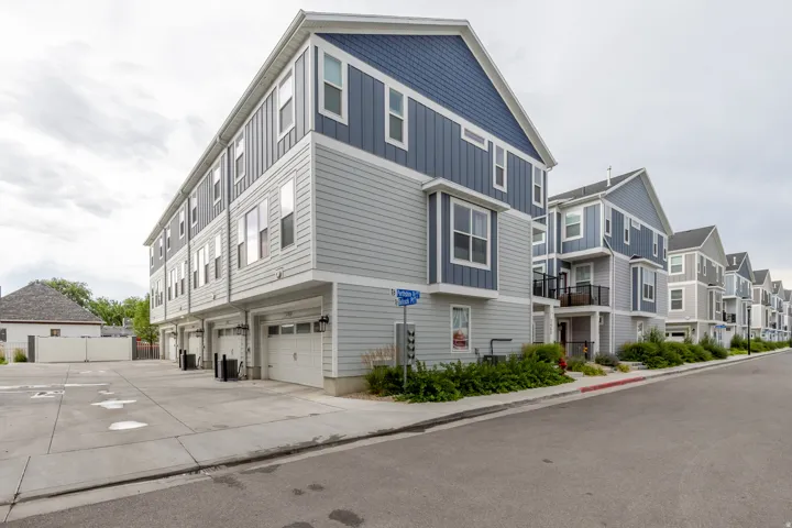 Modern multi-story facade featuring light gray horizontal siding and contrasting blue vertical siding