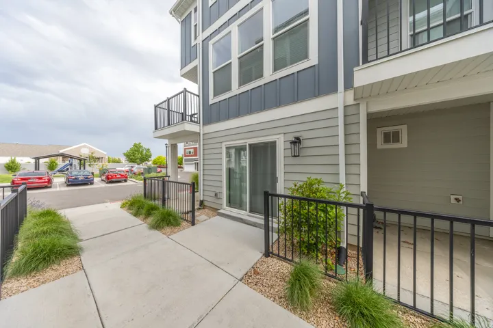 Townhome exterior featuring horizontal siding in two tones, a ground-level patio with black metal railing, and a sliding glass door entry