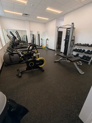 Fitness center featuring resilient rubber flooring, perimeter mirrors, and recessed lighting