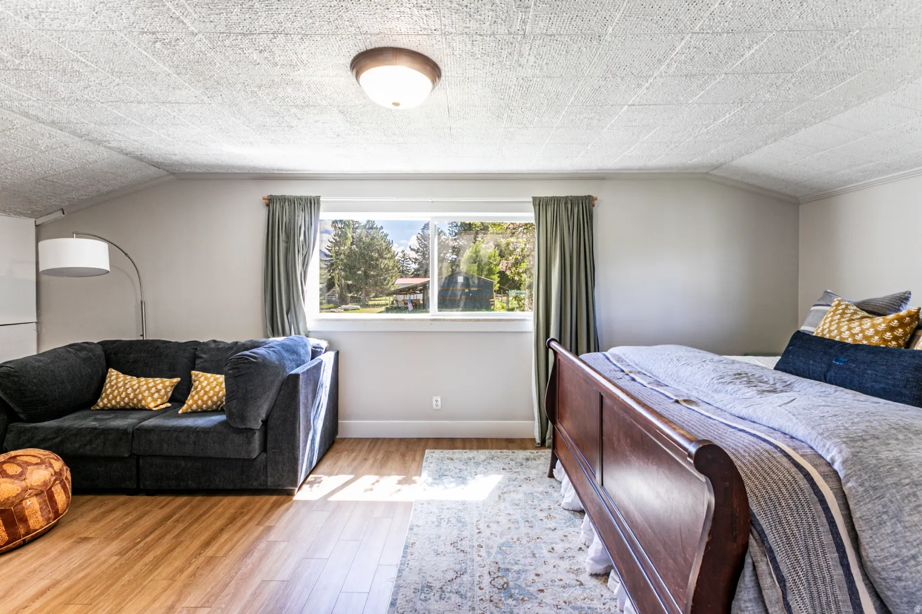 Spacious room featuring wood-finish flooring, light grey walls, and a large window