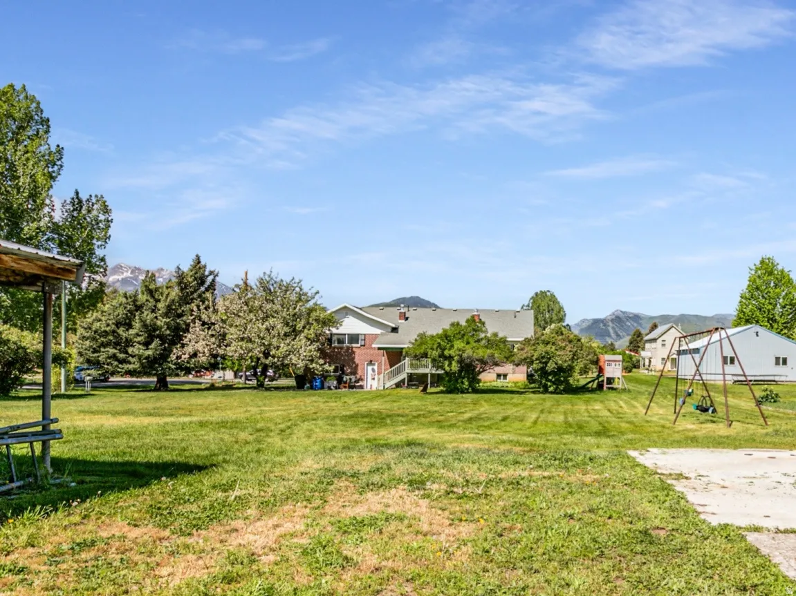 Expansive lawn area featuring a storage shed, concrete pad, and mature perimeter trees