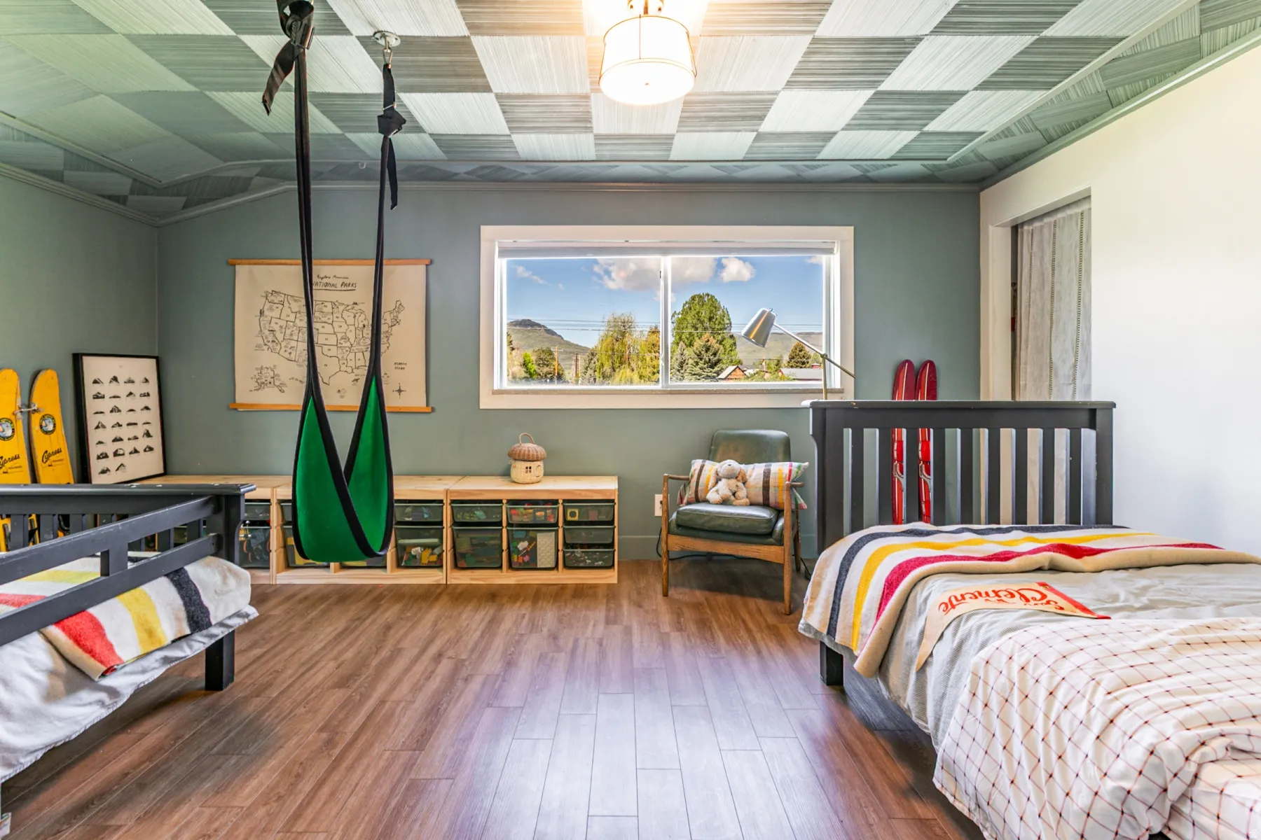Room featuring wood-finish flooring, a checkered ceiling, built-in storage units, and a window presenting a mountain backdrop