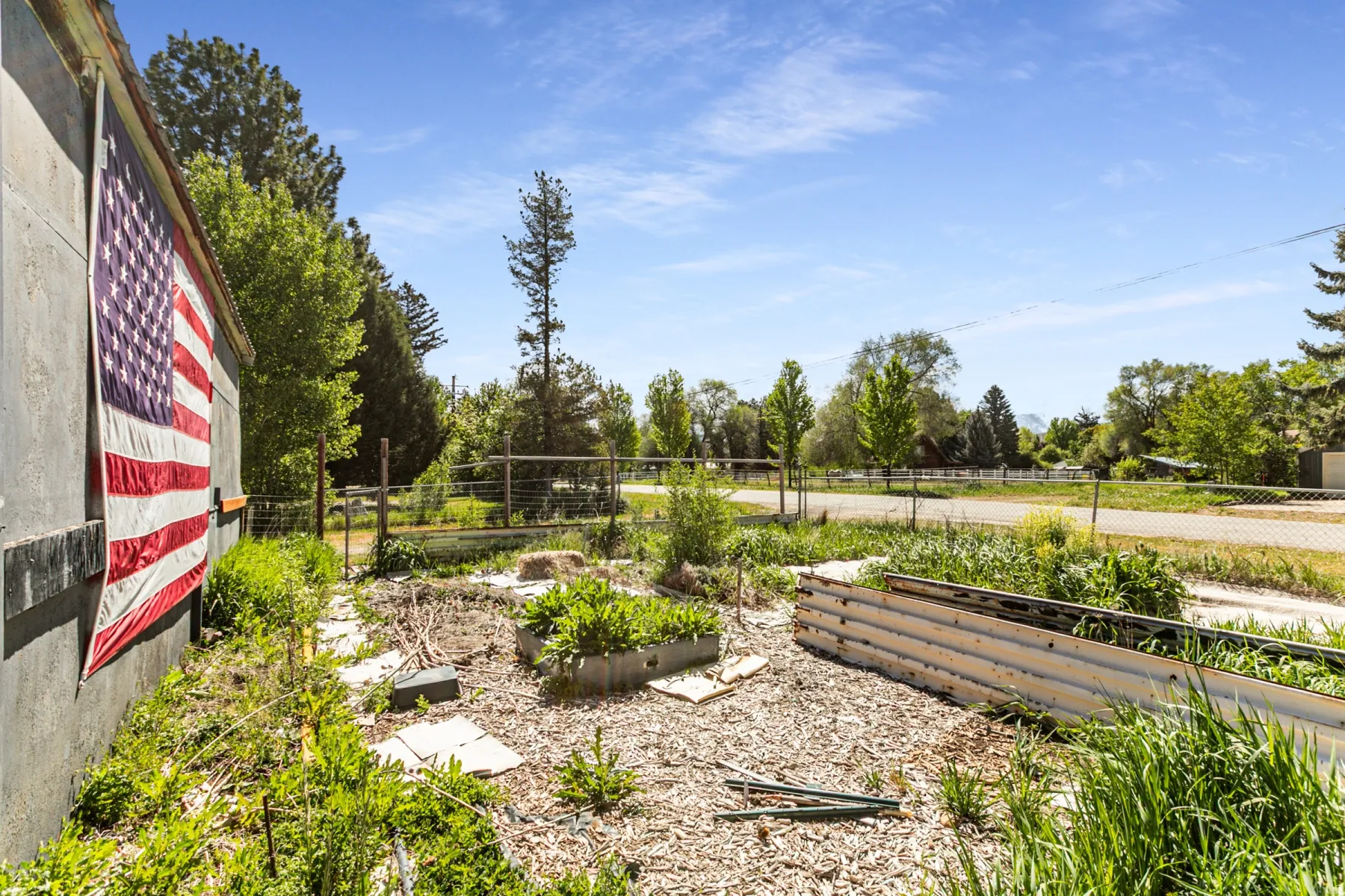 Outdoor space featuring raised garden beds, established perimeter fencing, and mature trees
