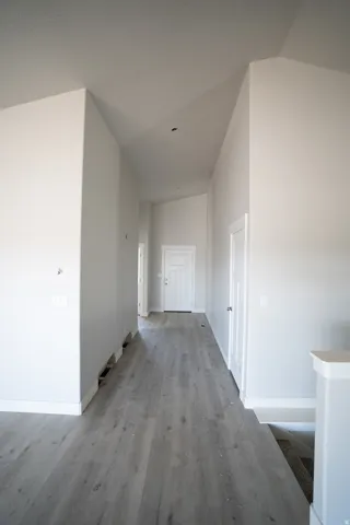Entryway featuring wood-finish flooring, vaulted ceilings, white trim, and a paneled door