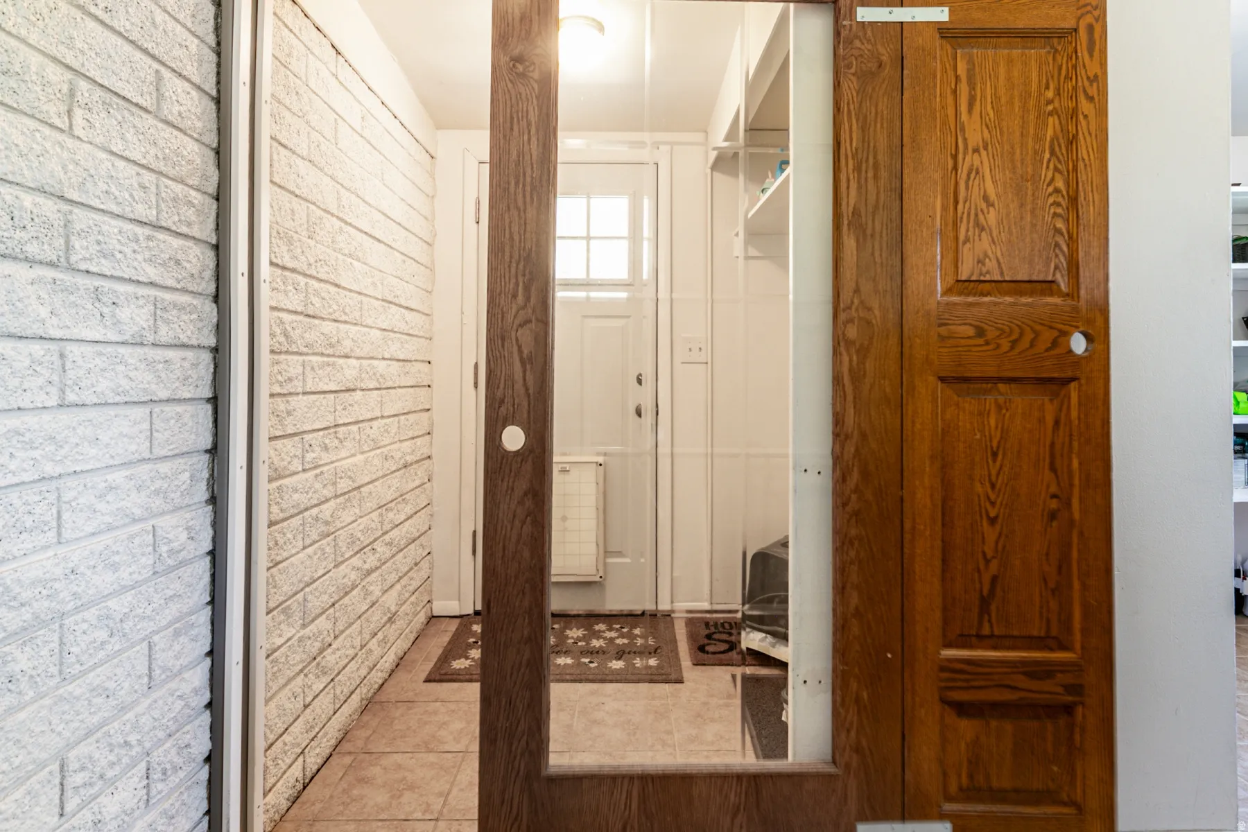 Wooden barn doors to back entry and laundry area with  white painted brick wall, and overhead lighting.