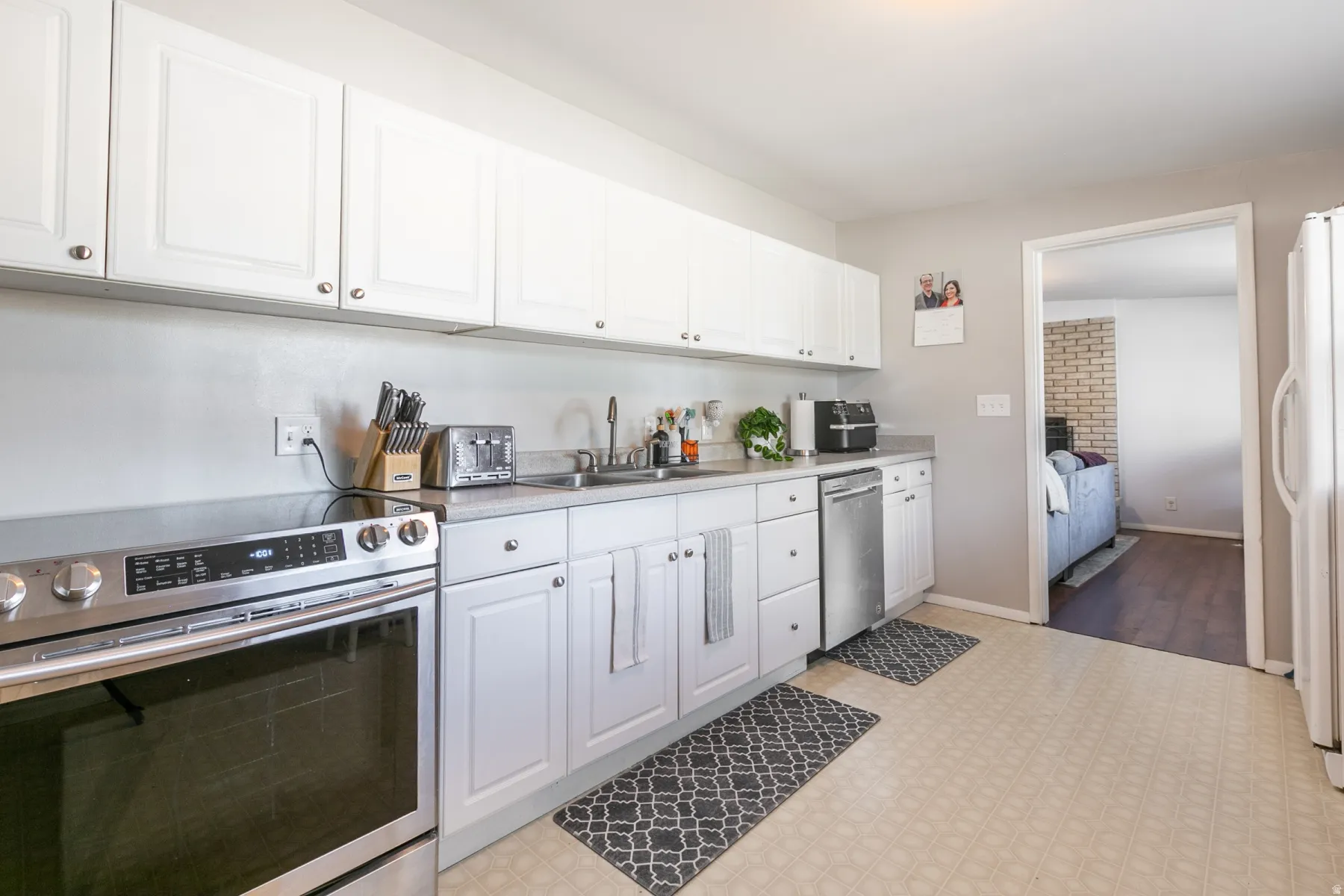 White cabinetry, newer stainless steel range, stainless steel dishwasher.
