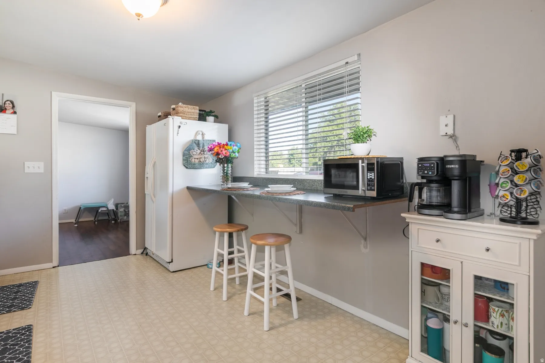 Kitchen with light-toned flooring, built-in breakfast bar, and a window with blinds