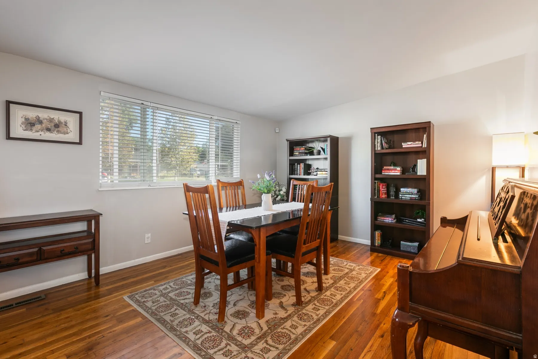 Hardwood flooring, neutral wall tones, and a large window with blinds