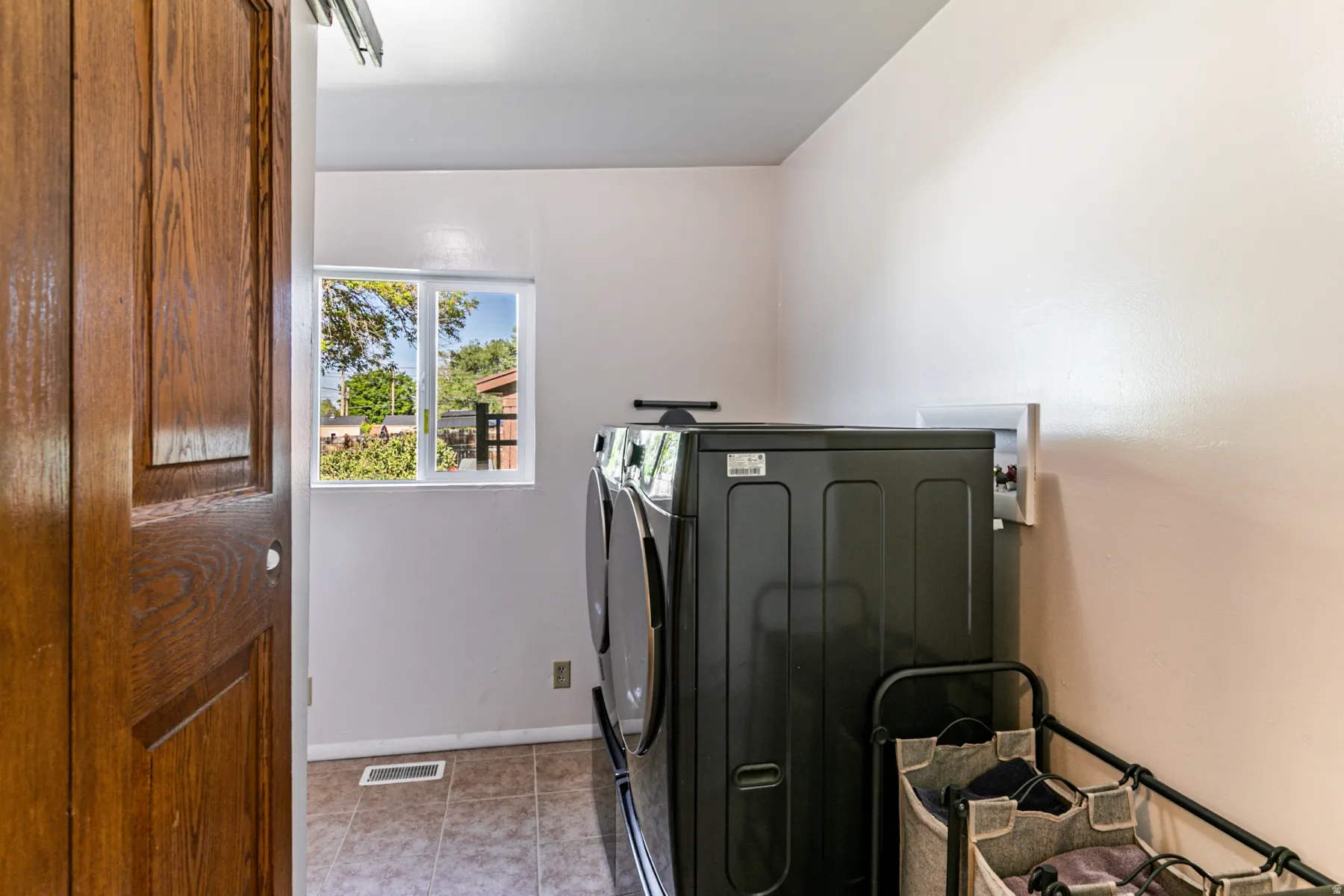Laundry area featuring tile flooring, a window providing natural illumination, and a wooden sliding door