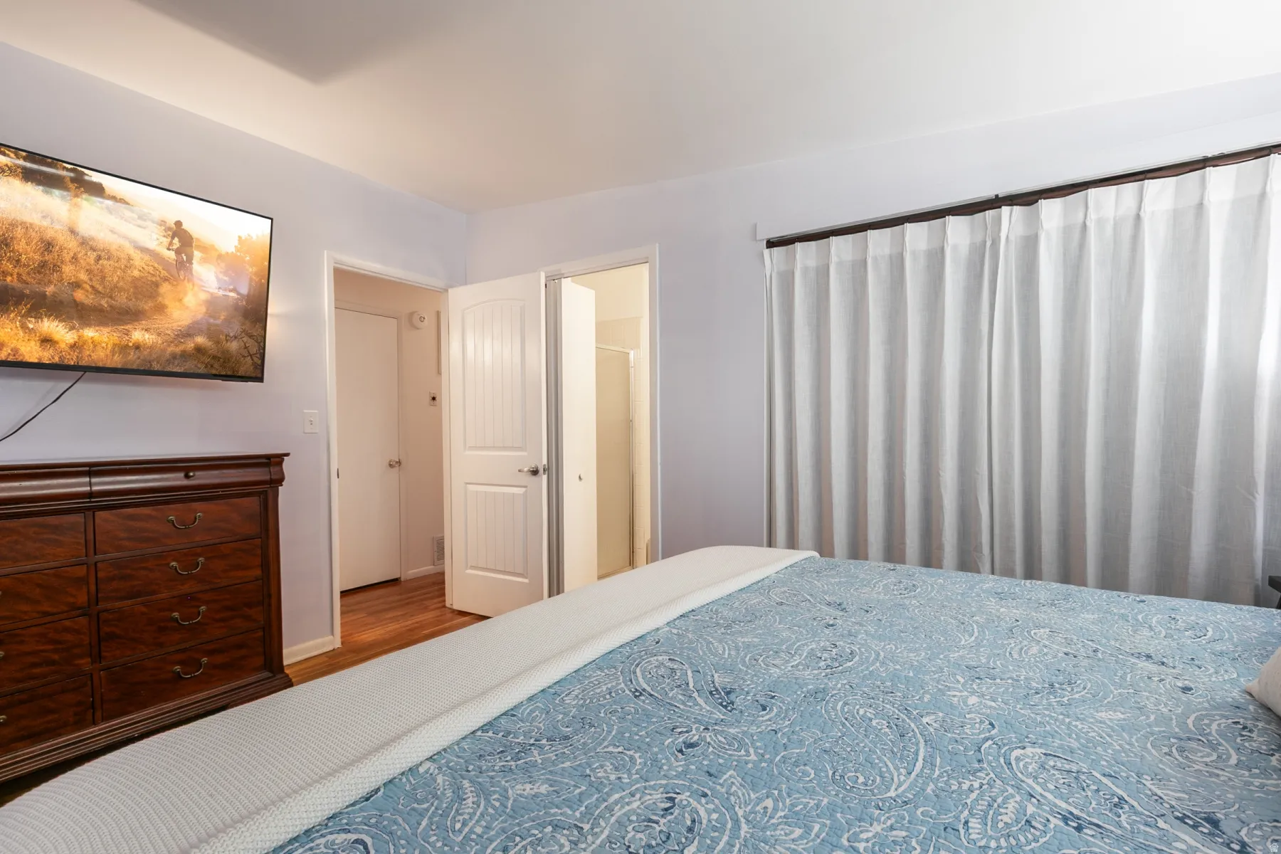 Primary bedroom with king-size bed, hardwood flooring, large closet, soft wall color.