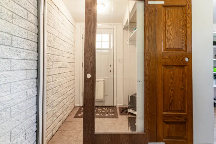 Wooden barn doors to back entry and laundry area with  white painted brick wall, and overhead lighting.