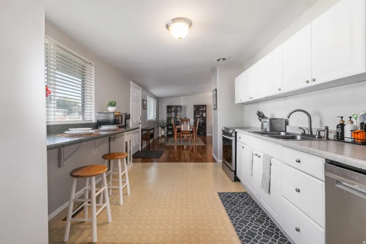 White cabinetry with stainless steel appliances, a breakfast bar.