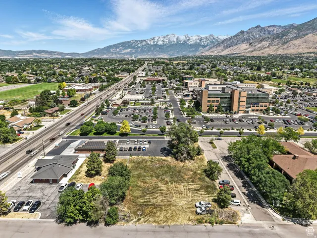 Expansive undeveloped lot with street frontage, surrounded by established landscaping, and positioned near commercial buildings