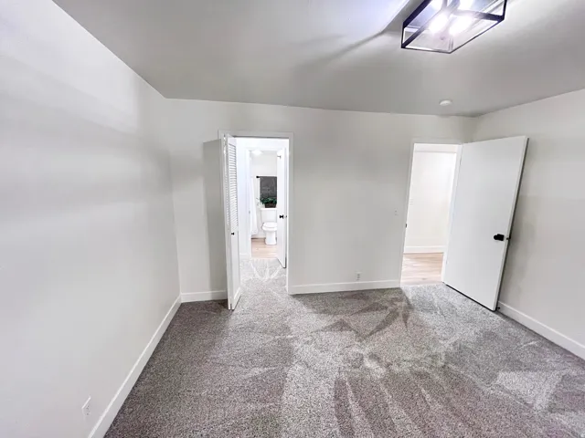 Second Bedroom featuring tall baseboards, cozy plush carpet, warm tones, and convenient bathroom access through a walk-in closet
