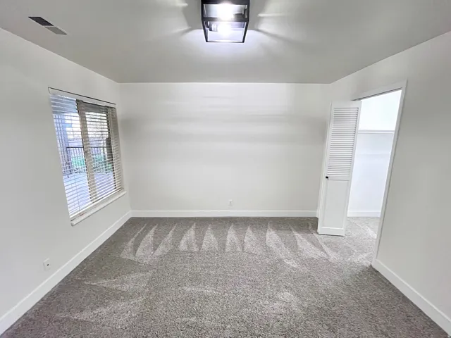 Second Bedroom featuring tall baseboards, cozy plush carpet, warm tones, and convenient bathroom access through a walk-in closet