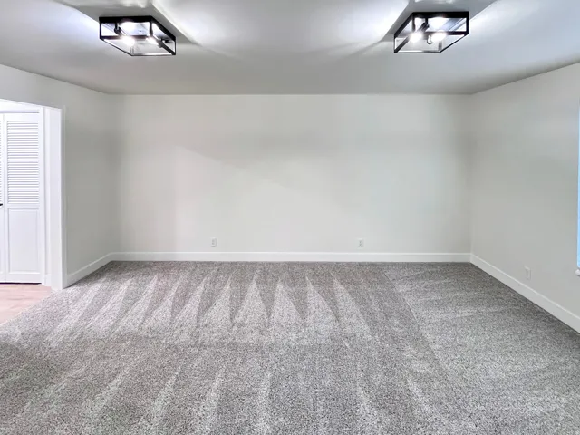 Primary Bedroom featuring tall baseboards, cozy plush carpet, warm tones, and convenient bathroom